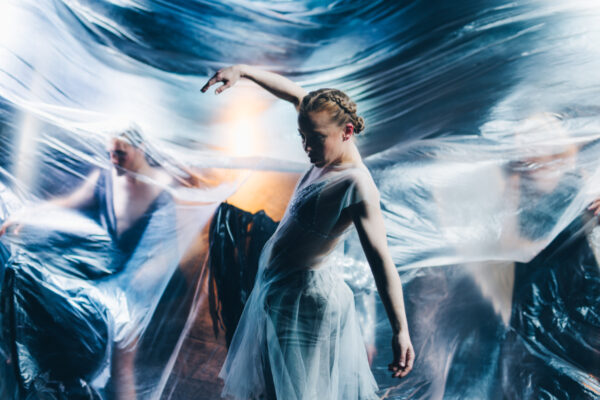 Etualalla tanssiva nainen, takana epäselviä ihmishahmoja.